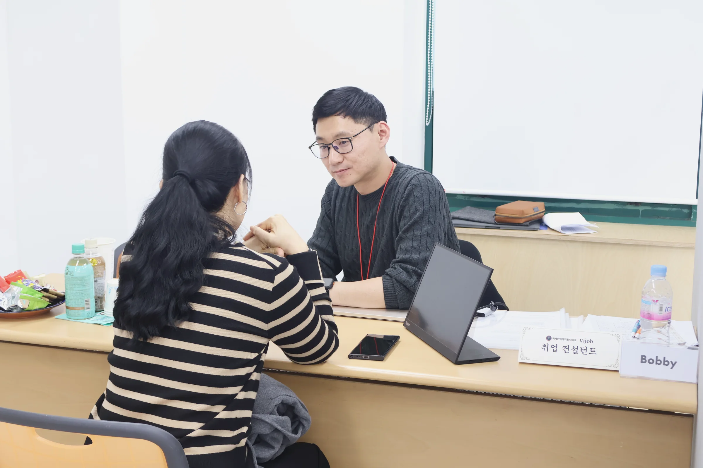 상담 데스크에서 노트북을 앞에 두고 유학생과 1:1로 이야기하는 포리덤 직원.